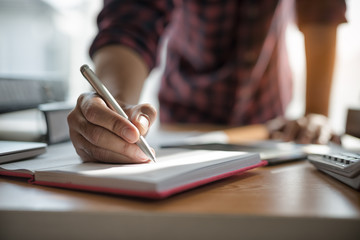 Fototapeta premium Hand of businessmen holding pen while writing notes in the book during the meeting..