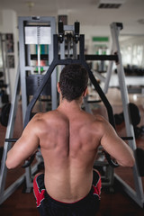 Naklejka premium Young attractive adult man exercising and doing weight lifting at fitness gym. Sport training indoors.