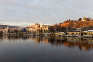 Fototapeta na wymiar Sunny snowy early morning Prague Lesser Town with gothic Castle above River Vltava, Czech republic