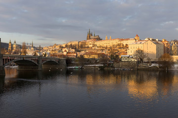 Sunny snowy early morning Prague Lesser Town with gothic Castle above River Vltava, Czech republic