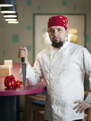 Portrait of a fashionable chef with a knife in bandana