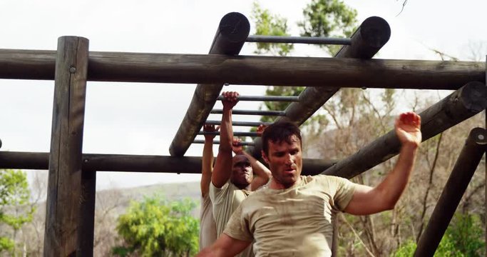 Military soldiers climbing monkey bars 