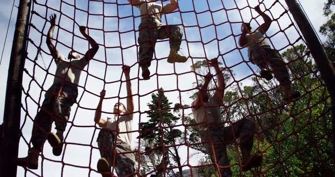 Military troops climbing a net during obstacle course 