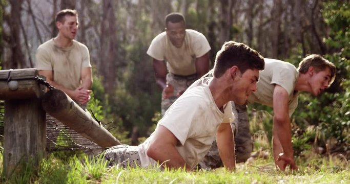 Military soldiers crawling under the net during obstacle course 