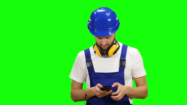 Engineer dials a message on his phone. Green screen