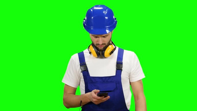 Builder dials a message on his phone. Green screen