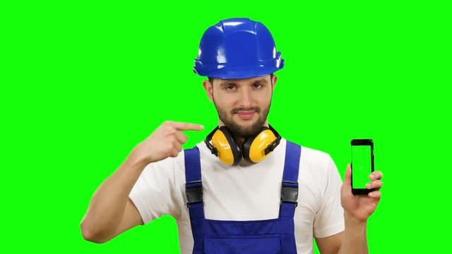 Man in a builder's suit advertises a smartphone. Green screen. Mock up