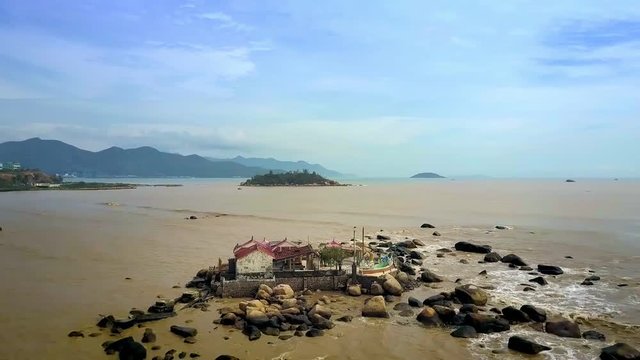 Buddhist Temple on Stones in Sand Sea against City Scape