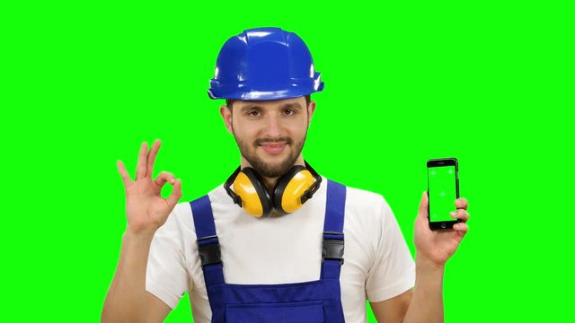 Foreman holds a phone in his hands and shows a thumbs up. Green screen. Mock up