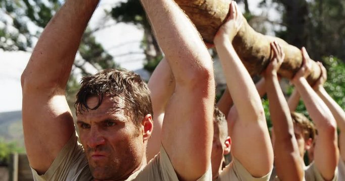 Military troops carrying heavy wooden log during obstacle course 