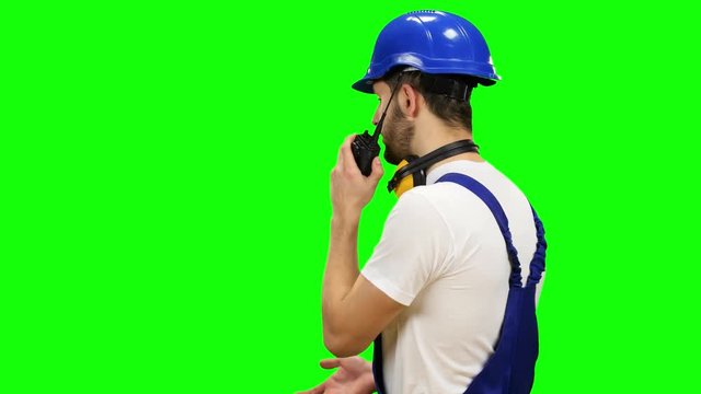Builder speaks in a walkie talkie to the colleagues. Green screen