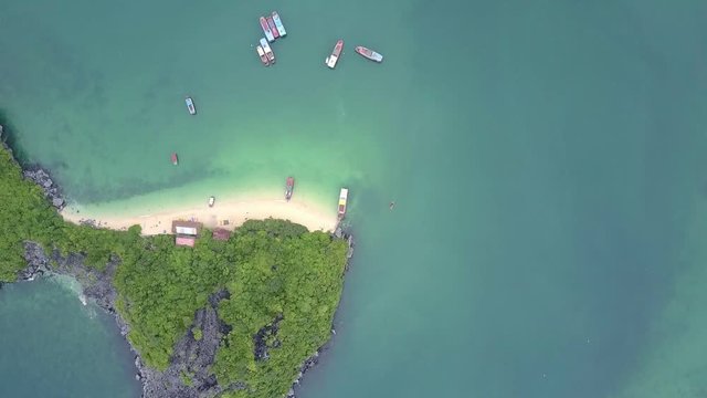 Drone Rotates over Green Island with Sand Beach in Azure Bay