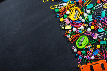 Top view of colorful office equipment with copy space on black chalkboard background. Education concept.
