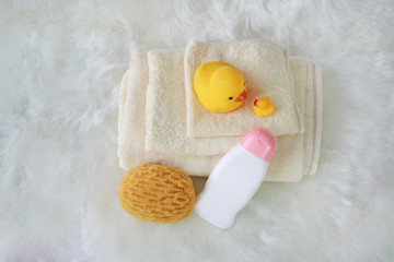 Children's bath products and hygiene items on white fur. Top view.