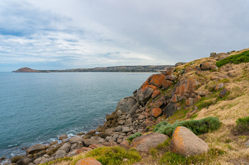 Fototapeta na wymiar Coastline with high cliff covered with rocks and colorful lichen