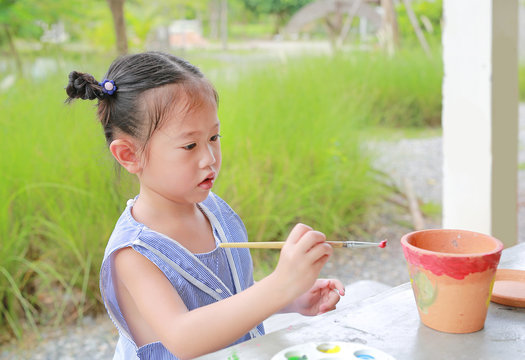 Asian kid girl paint on earthenware dish.