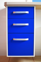 Bright blue modern chest of drawers with three drawers in bathroom.