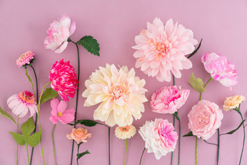 Crepe paper flowers on pink wooden background