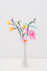Bouquet of crepe paper cosmos and sweet peas in a vase on white