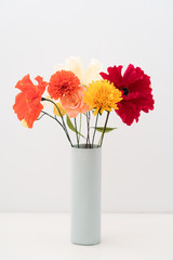 Bouquet of crepe paper marigold, poppies and roses flowers in a vase on white