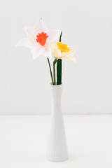 Bouquet of crepe paper daffodil flowers in a vase on white
