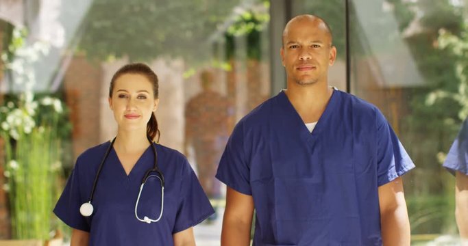 4K Young confident medical workers looking directly to camera in modern private healthcare clinic. Slow motion