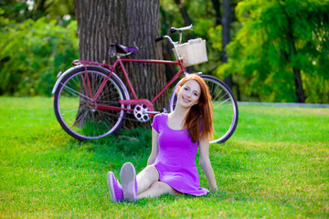 girl sitting on grass near vintage bike