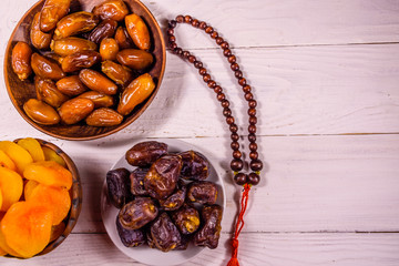 Date fruits and rosary on wooden table. Top view