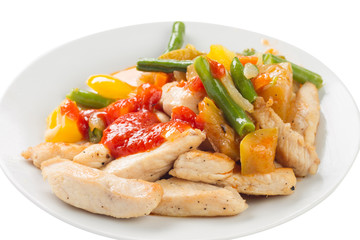 chicken pieces fried with vegetables on a plate, with ketchup, white background
