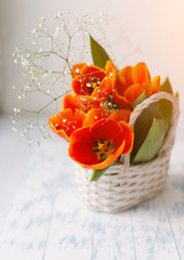 Tulips in a basket on a white wooden background