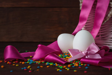 Eggs, Pink Tape, Colored Sweets, White Basket on the Wooden Background. Easter concept