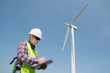 Fototapeta premium Electric Engineer writing report on Clipboard with Wind turbine power Generator