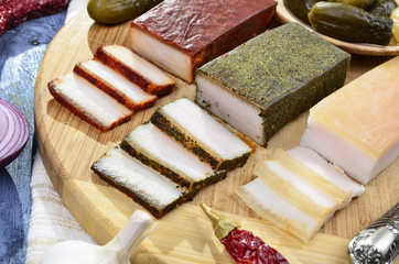 Smoked  bacon, pickles, onions ,garlic, paprika on a  wooden table - rustic style on blue vintage background.