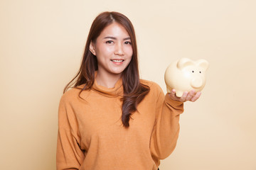 Young Asian woman with a pig coin bank.