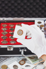 Hand in the glove holds gold collector coin
