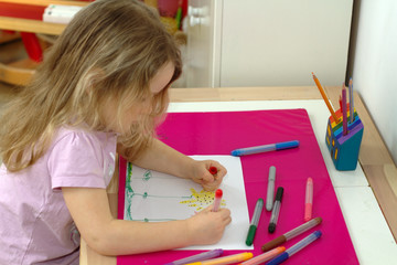 Little blonde girl paints with felt-tip pens