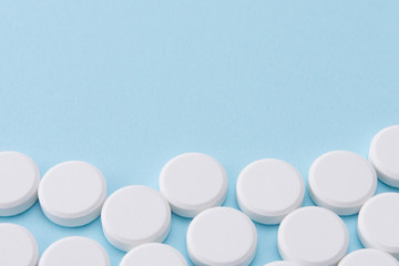 white pills on blue background with copy space