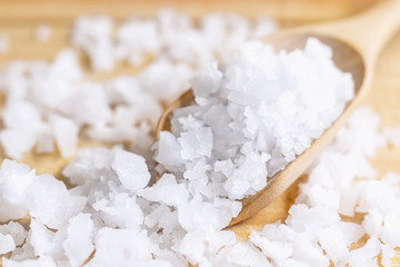 Sea salt in a wooden spoon on the table. Sea salt is used for seasoning, preserving food and making beauty treatment the scrub with salt. selective focus.