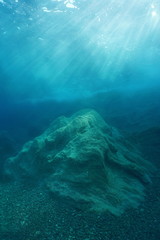 A rock underwater on the seabed with natural sunlight below water surface, Mediterranean sea, Costa Brava, Catalonia, Spain