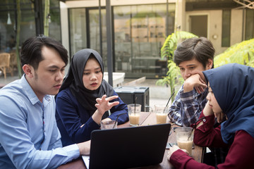Small Creative Team of South East Asian Young People Looking at a Laptop. Having Meeting and Discussion at Outdoors Cafe. - 195448371