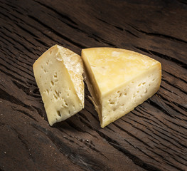Pieces of homemade cheese on the wooden background.
