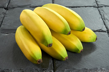 Kiść dojrzałych bananów na czarnym tle (kamień łupkowy)