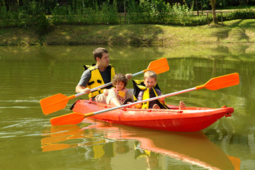 Happy family with two kids enjoying kayak ride on beautiful river. Father with little girl and boy...