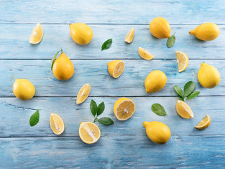 Ripe lemons and lemon leaves on blue wooden background. Top view.