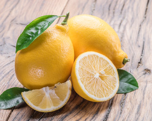 Two ripe lemon with lemon leaves on old wooden table. Close-up.