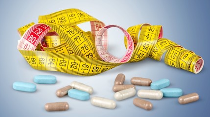 Tablets and tapemeasure on background