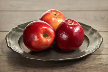Trzy czerwone jabłka na metalowym talerzu