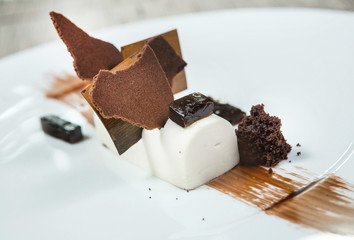 Dessert - Chocolate puff cake decorated with chocolate pieces. White chocolate. Dish of the restaurant