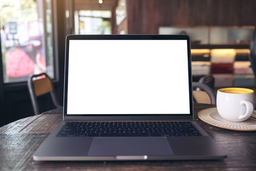 Fototapeta premium Mockup image of laptop with blank white desktop screen and coffee cup on wooden table in modern cafe