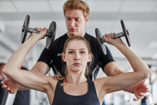 Junge Frau beim Hanteltraining mit Trainer